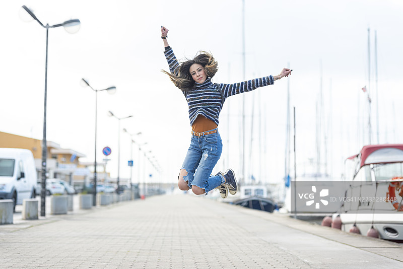 女人在码头的步道上奔跑跳跃图片素材