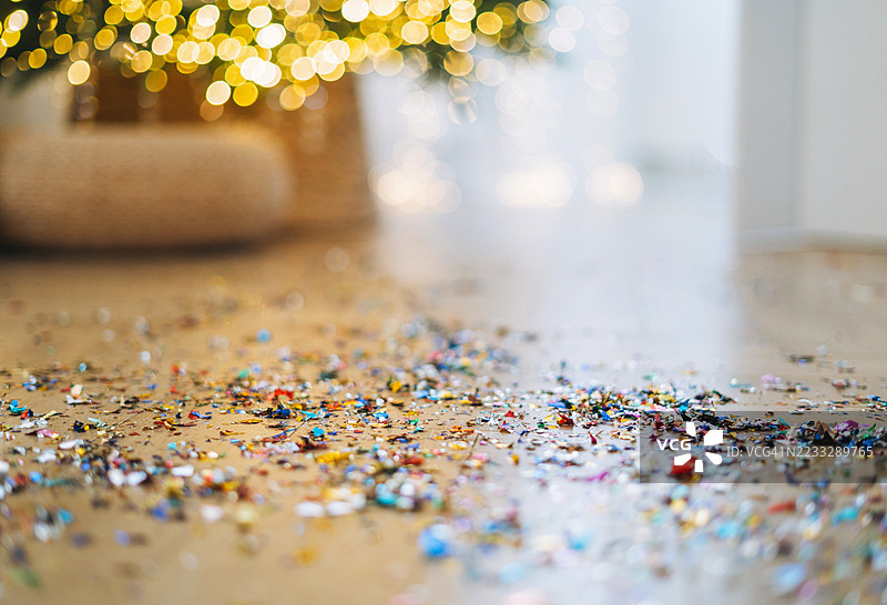 新年庆祝背景，五彩缤纷的纸屑洒落在地上，背景是圣诞树的虚化效果图片素材