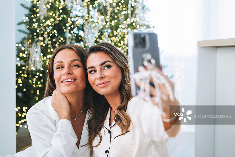快乐的女性朋友们在家庆祝时一起拍摄自拍瞬间图片素材
