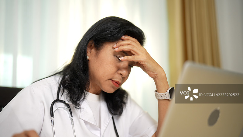 女医生在使用笔记本电脑时感到头痛图片素材
