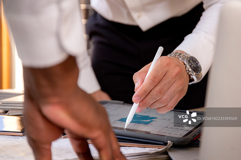 工程师和建筑师团队在施工现场开会，讨论室内设计的规划和策略，同时在笔记本电脑上查看信息，并在平板电脑上写作。图片素材