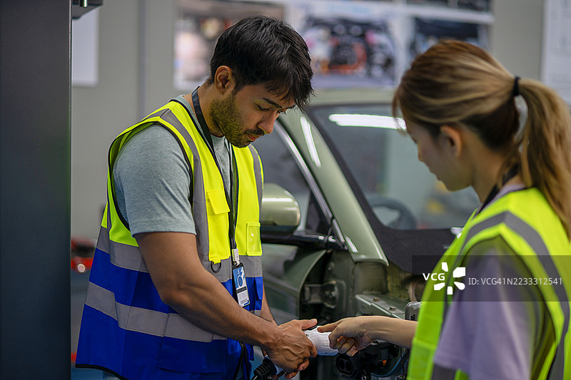 机械师在电动车维修车间工作。图片素材