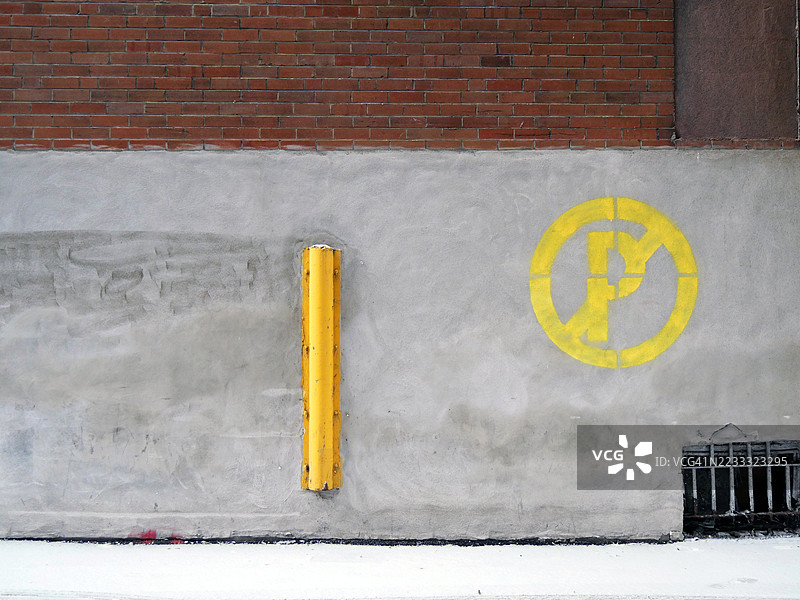 蒙特利尔，魁北克，加拿大的一面风化的混凝土和砖墙特写，墙上有禁止停车的标志。地面覆盖着雪。阳光照射，自然色彩。图片素材