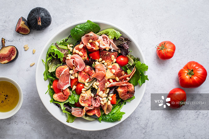 自制沙拉盘，配有新鲜无花果、沙拉火腿、西红柿和油醋汁图片素材