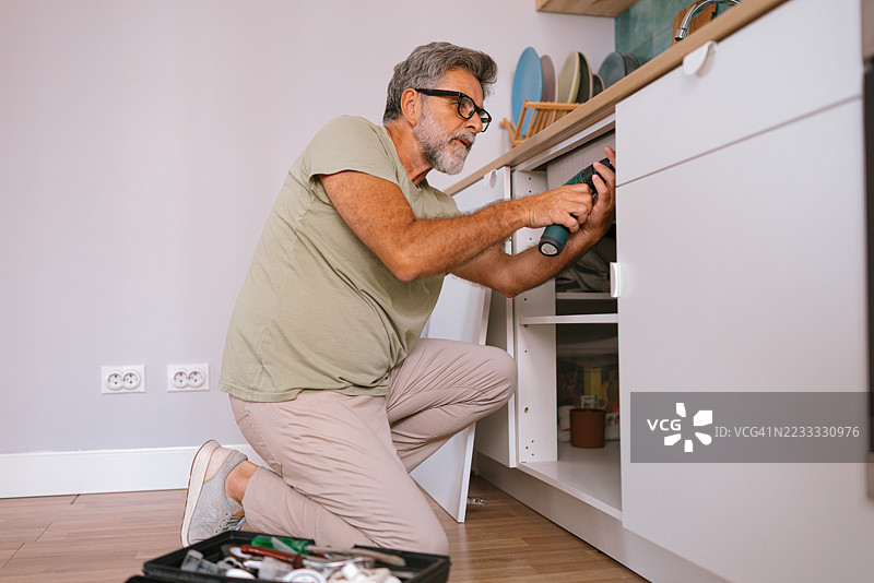 男子使用电钻安装厨房橱柜图片素材