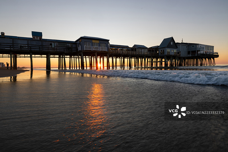 在老橡树海滩码头观看日出的人的剪影图片素材