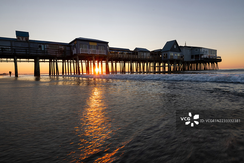 在老橡树海滩码头观看日出的人的剪影图片素材