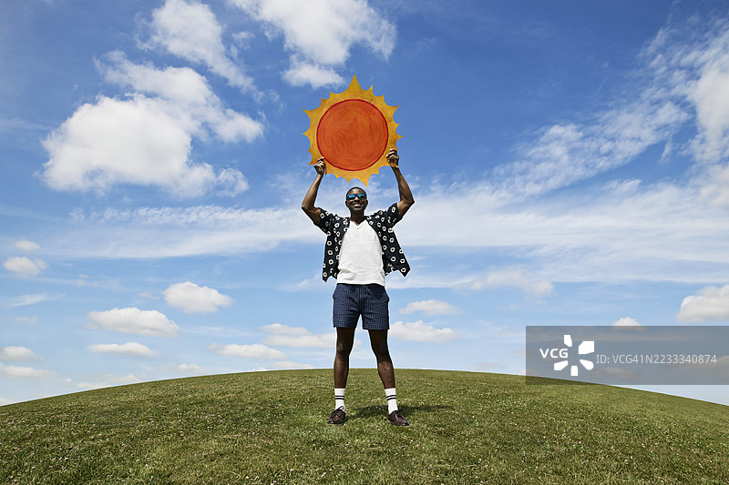 男人在天空中举着剪出的太阳形状图片素材