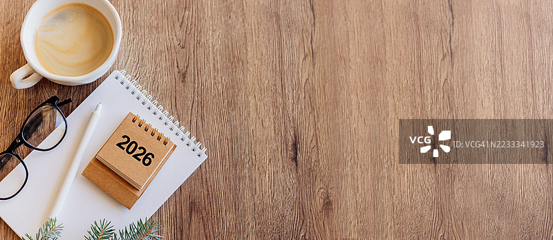 2026年桌面日历放在桌子上，留有空白空间。新年装饰与圣诞灯光。新年规划概念。网站横幅。图片素材