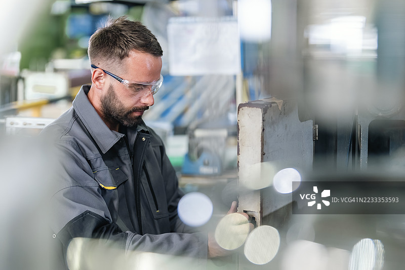 技术员在工厂中操作塑料注塑机的控制面板。图片素材