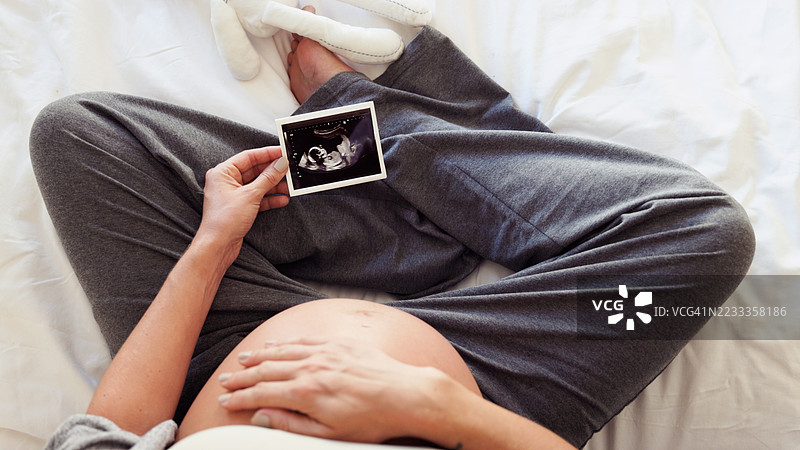 孕妇展示超声波照片 - 床上特写肚子图片素材