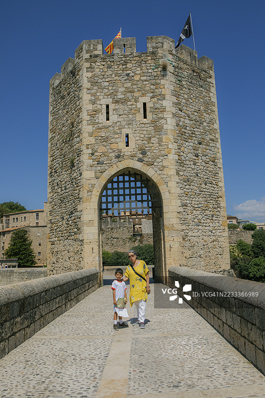 祖母和孙子走过西班牙加泰罗尼亚贝萨卢的一座石桥图片素材