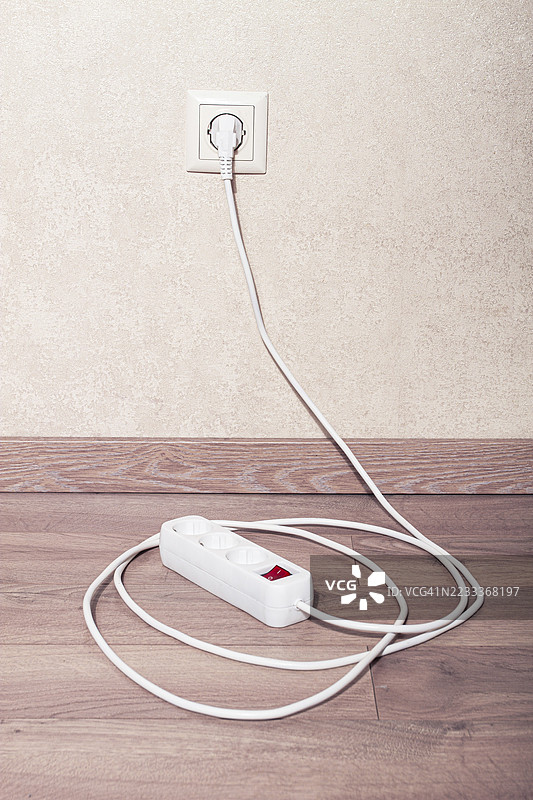 电源插座连接到明亮房间木地板上的墙壁插座图片素材