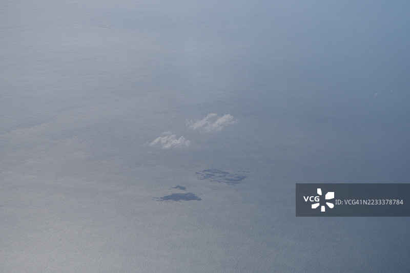 海洋上空的鸟瞰图，展示了小岛和云朵图片素材