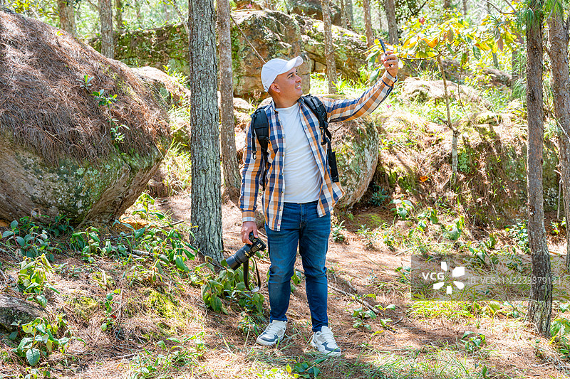 一位年长男性在森林中徒步时自拍图片素材