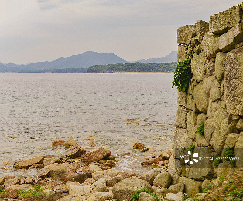宁静的海岸风景，岩石海岸和远处的山脉，日本图片素材