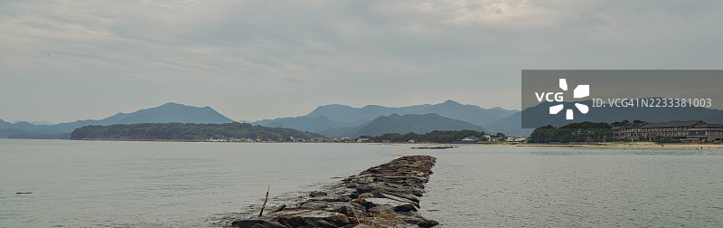 宁静的海岸风景，背景是山脉和阴云密布的天空，日本图片素材