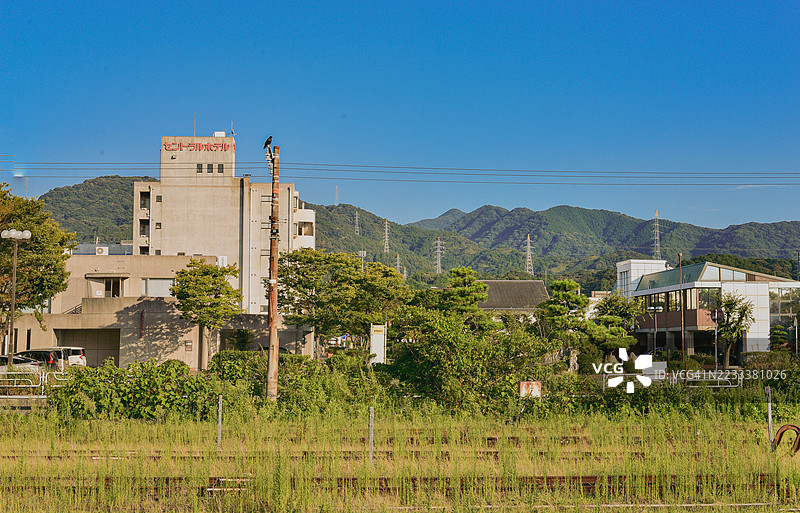 日本清澈蓝天下的城市景观，建筑与山脉相映成趣图片素材