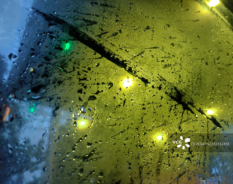 玻璃窗上的雨滴与模糊的背景灯光图片素材