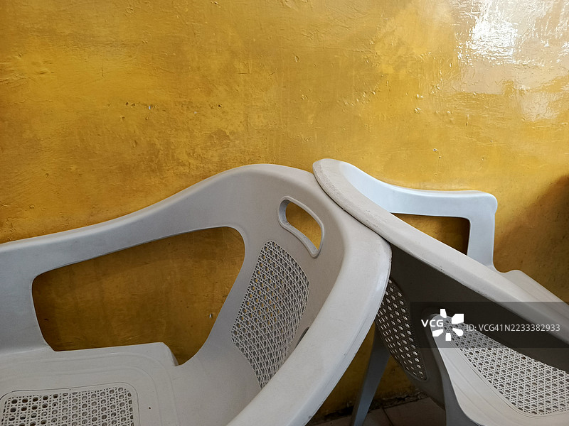两把塑料椅子靠在黄色墙壁上图片素材