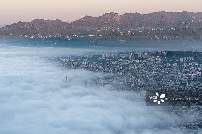 被雾气笼罩的城市景观鸟瞰图，背景是山脉，博兹特佩，土耳其图片素材