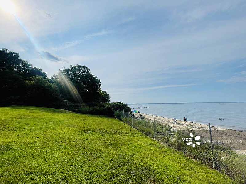 阳光明媚的海滩与绿树环绕的海洋景观图片素材