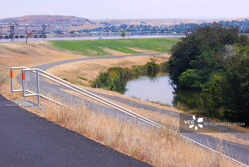 乡村风景中蜿蜒的道路，旁边有一个池塘和远处的山丘，路易斯顿，美国图片素材