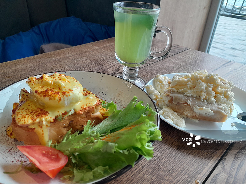美味的早餐：班尼迪克蛋和绿色果汁摆放在木桌上图片素材