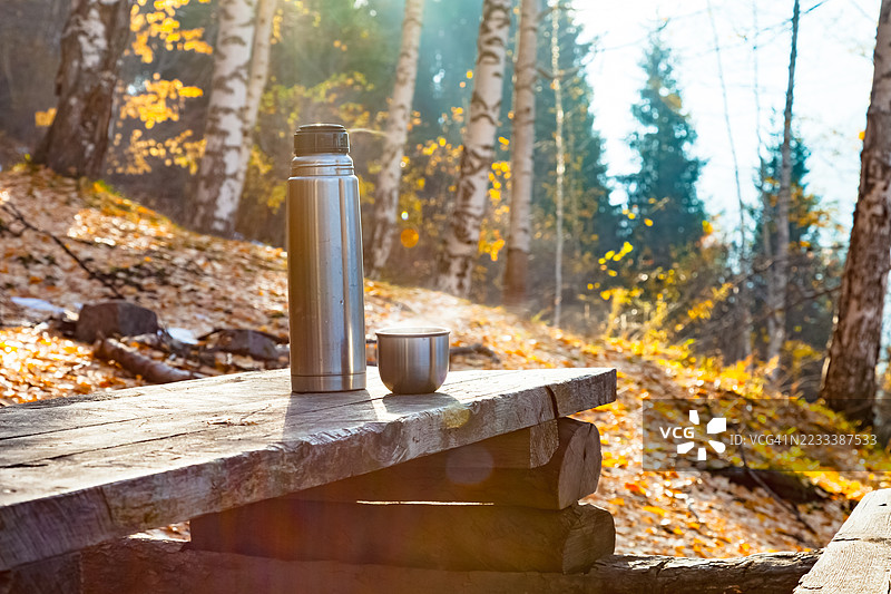 秋季森林中的木长椅上放着保温瓶和杯子，哈萨克斯坦图片素材
