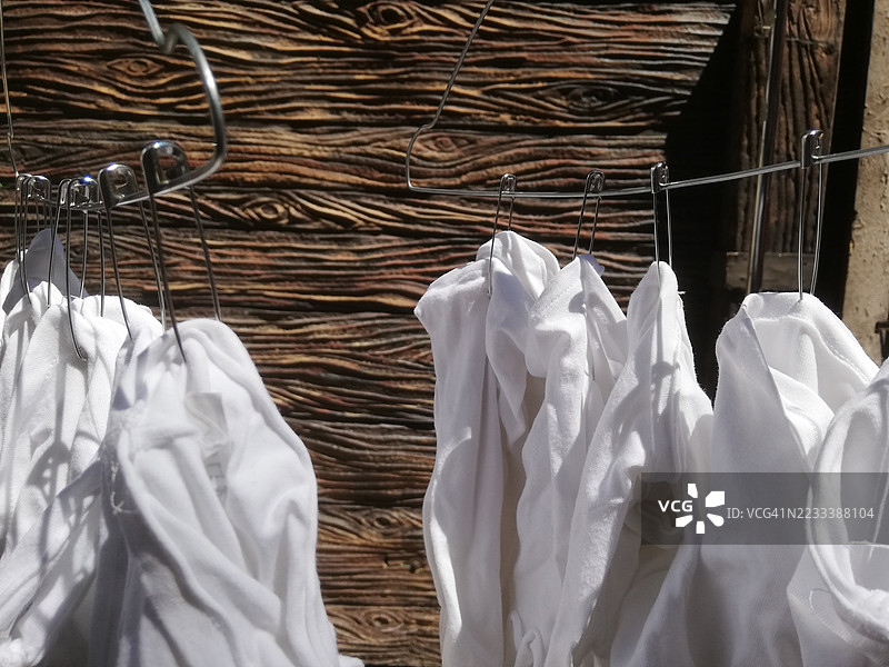 白色衣物在木质背景的晾衣绳上晾干图片素材