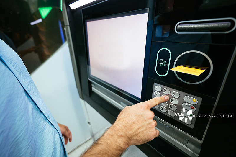 现代银行设施中，夜间使用ATM机时人手的特写镜头图片素材