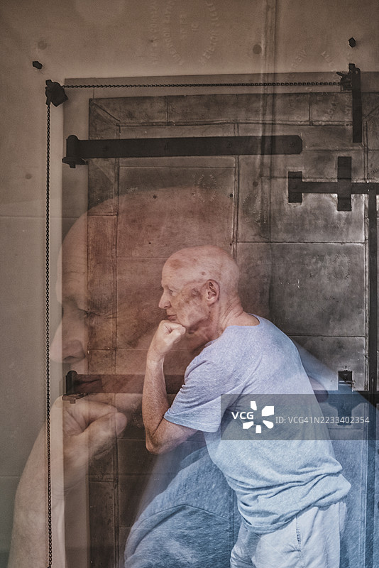 双重曝光的光头白人男性，摆出像奥古斯特·罗丹的“思考者”一样的姿势。这个姿势显得沉思和深思，代表着深刻的思考和高超的智慧。双重曝光增强了这些概念。图片素材