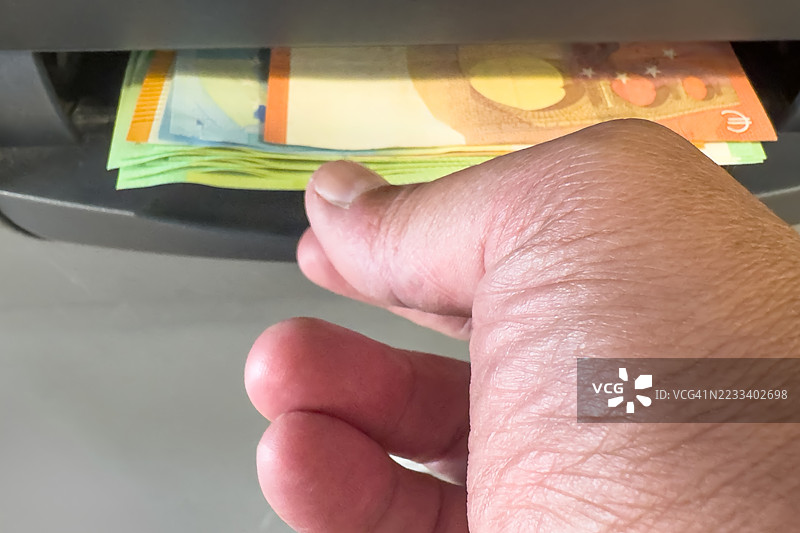 自动取款机旁有人手伸向欧元钞票图片素材