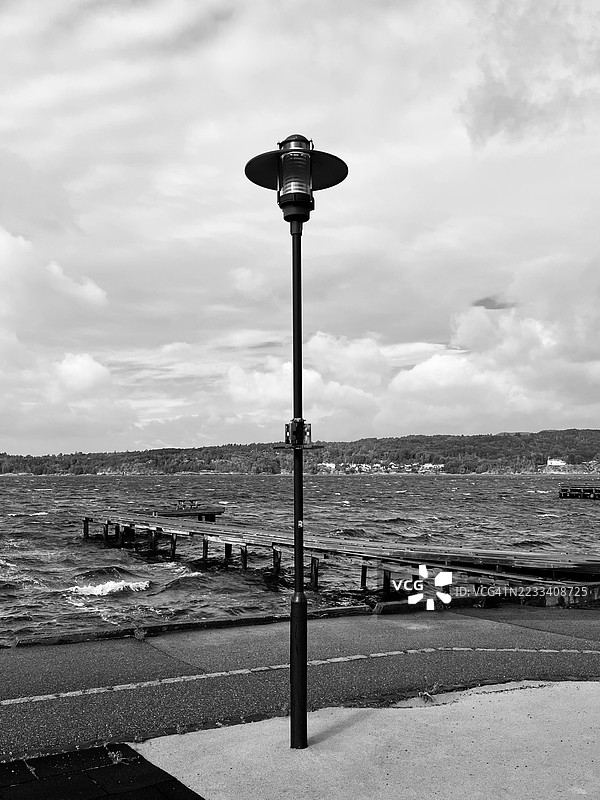 海边街灯的黑白视图，天空多云图片素材
