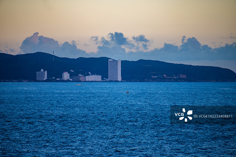 黄昏时分的海滨城市景观，背景是海洋和山脉，日本图片素材
