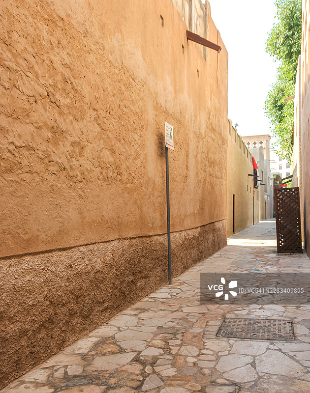 中东城市的狭窄小巷，石铺路面和米色墙壁，迪拜，阿拉伯联合酋长国图片素材
