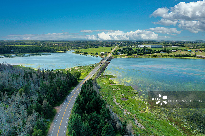 海岸公路的鸟瞰图，四周环绕着郁郁葱葱的绿树和水域图片素材
