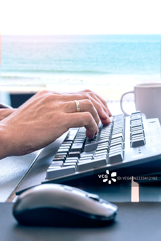 手在海景前的键盘上打字图片素材