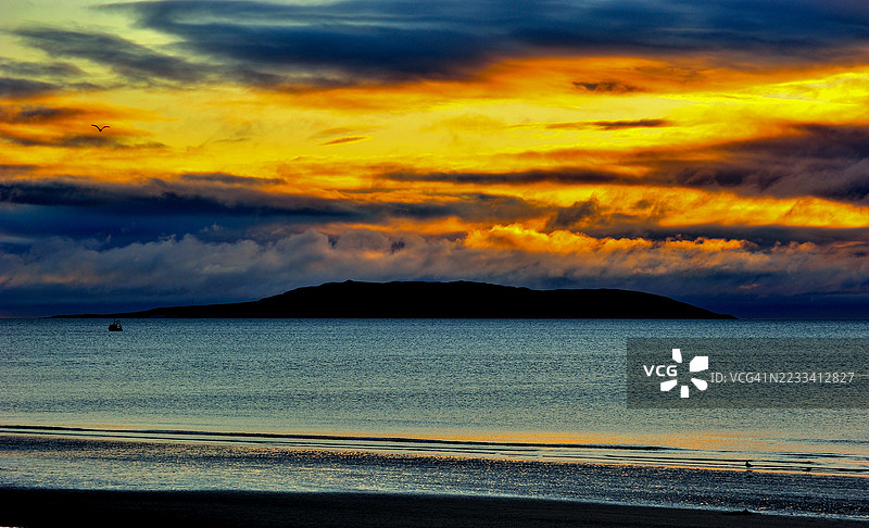 爱尔兰波特马尔诺克宁静海面上的戏剧性日落与岛屿剪影图片素材