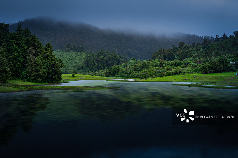 被郁郁葱葱的森林环绕的雾气弥漫的湖泊图片素材