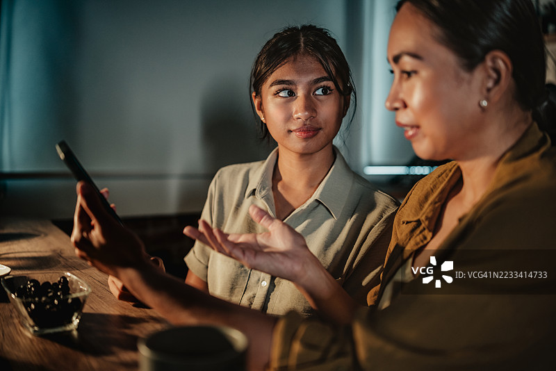 母女在家共享宁静的夜晚，进行有意义的对话，并通过手机增进感情。图片素材