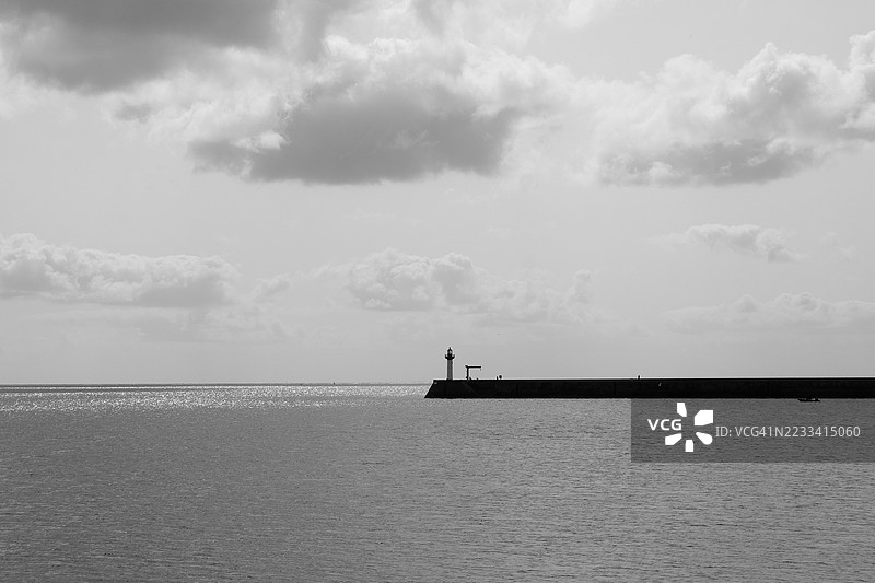 黑白色调的灯塔在云雾弥漫的天空下的码头上图片素材