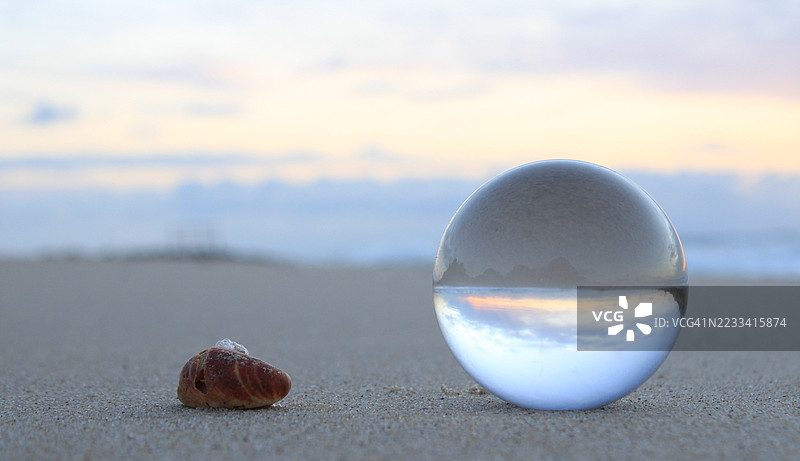 日落时分，沙滩上的水晶球和海螺图片素材