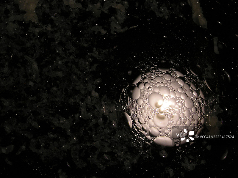 黑色表面上气泡和光的抽象特写图片素材