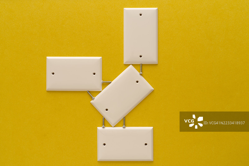 Abstract arrangement of white wall plates on a vibrant yellow background图片素材