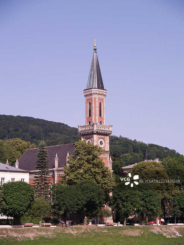 被郁郁葱葱绿树环绕的历史教堂塔楼，维也纳，奥地利图片素材