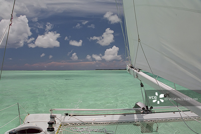 在生机勃勃的天空下，航行在碧绿色的海洋上图片素材