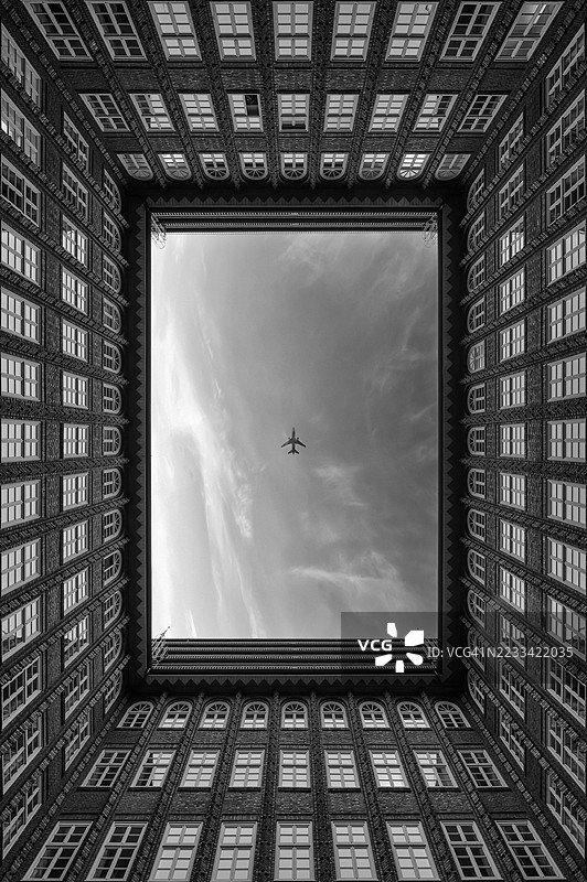 飞机飞过被建筑风格框住的庭院，汉堡，德国图片素材
