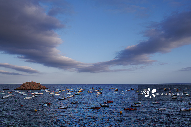 在西班牙托萨德马尔，平静海面下锚停的船只与戏剧性的天空图片素材