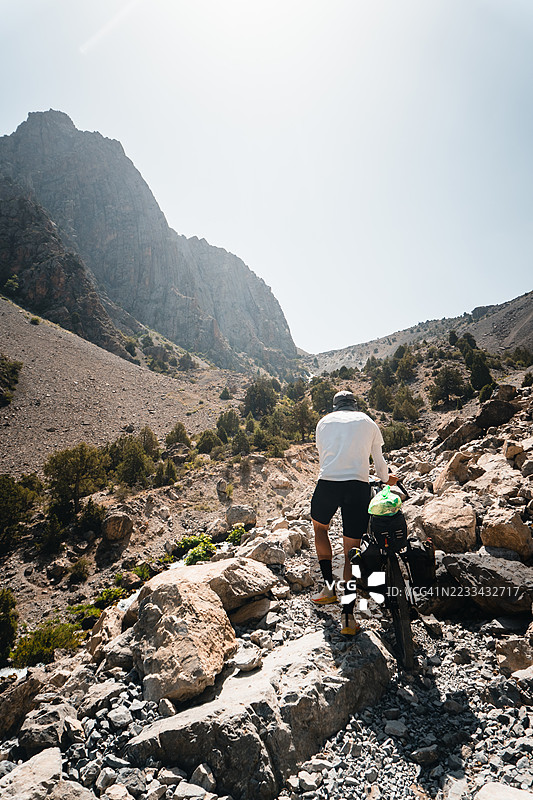 骑行者在山间小径上推着自行车图片素材